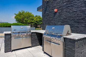 Two stainless steel barbecue grills on a patio
